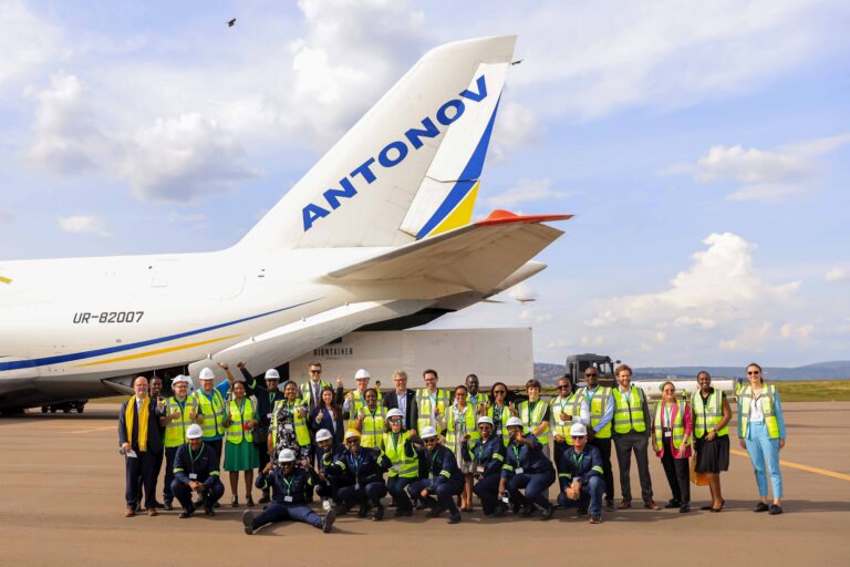 Photo de groupe de l'équipe sous la queue d'un avion sur le tarmac