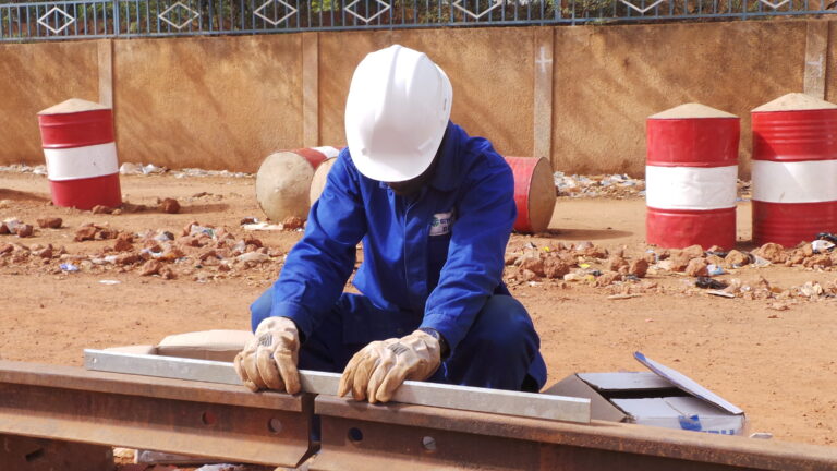Technicien ferroviaire en Afrique en train de d'assembler une éclisse de rail