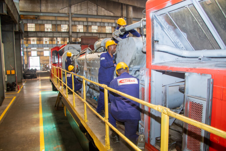 techniciens ferroviaires en phase d'inspection d'une locomotive dans un atelier de répartation