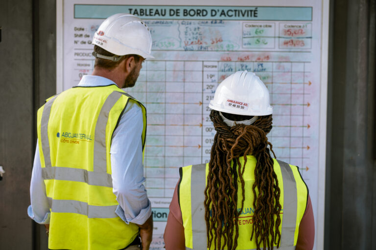 deux employés en tenue de sécurité regardant le tableau de bord d'activité dans le terminal d'Abidjan en Côte d'Ivoire