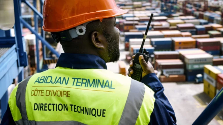 Employé avec tenue de sécurité avec son walkie talkie devant des conteneurs au terminal d'Abidjan